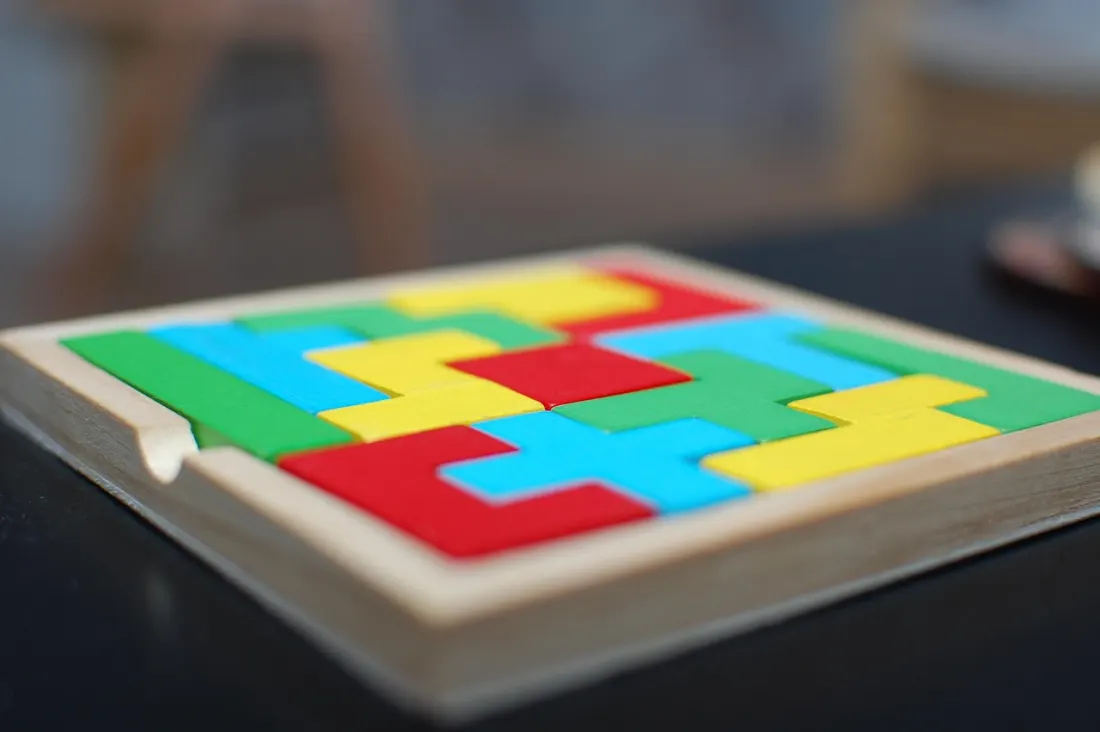 A wooden logic puzzle tray with bright interlocking pieces